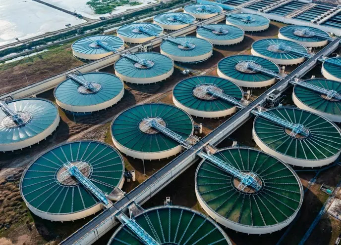 Water plant in a big open field with dying grass with flooded planes in the background on a birds eye view.